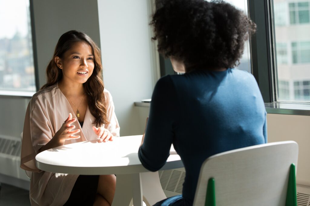 Two people talking over a desk 