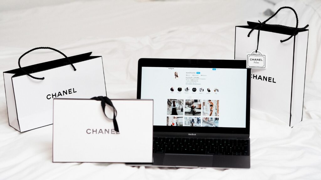 3 Chanel bags together with a laptop showing an Instagram feed in the middle. 