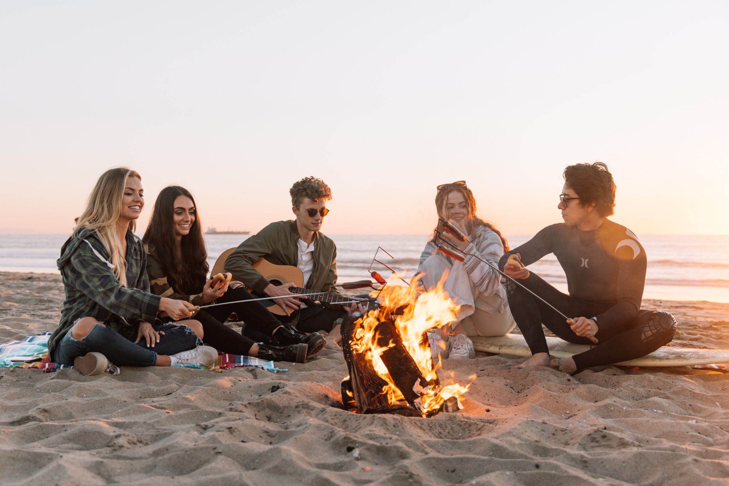 5 friends sitting around a campfire at sunset