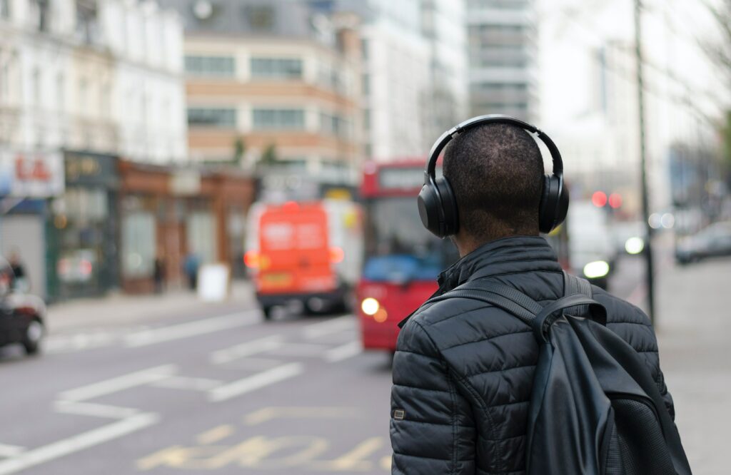 A man wearing headphones waiting for the bus.