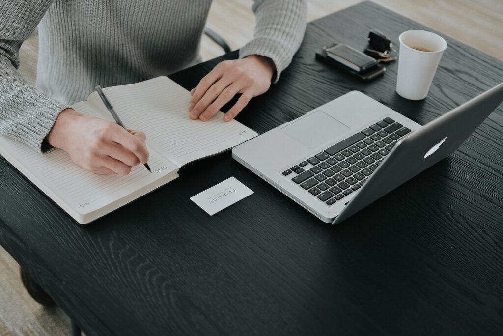 A person working on a laptop and writing notes