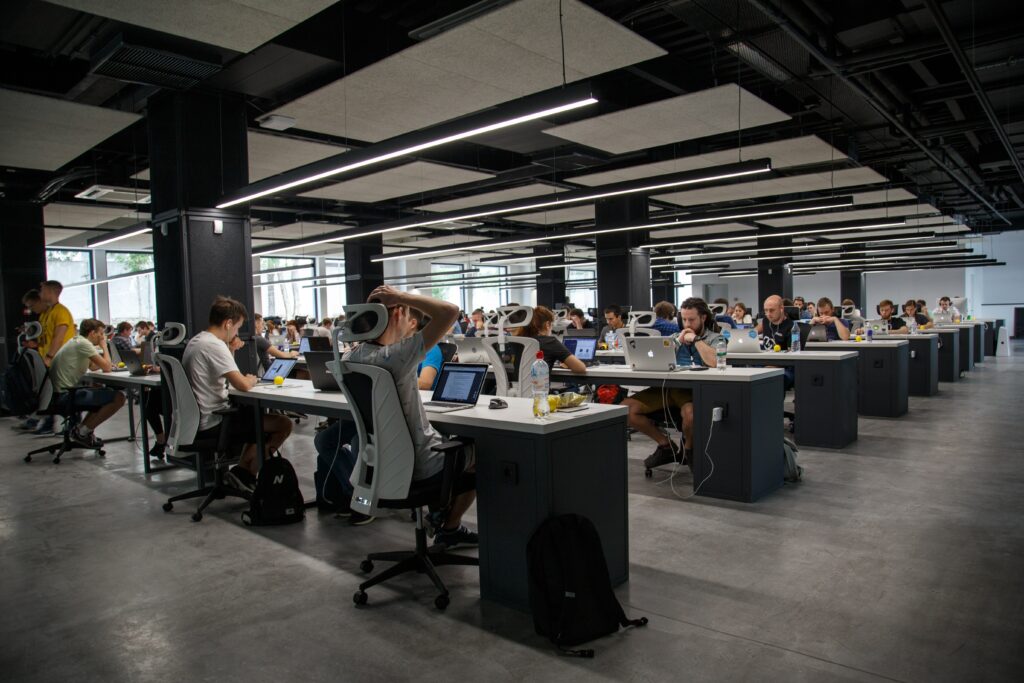 A group of people working at the desks in rows at their office.