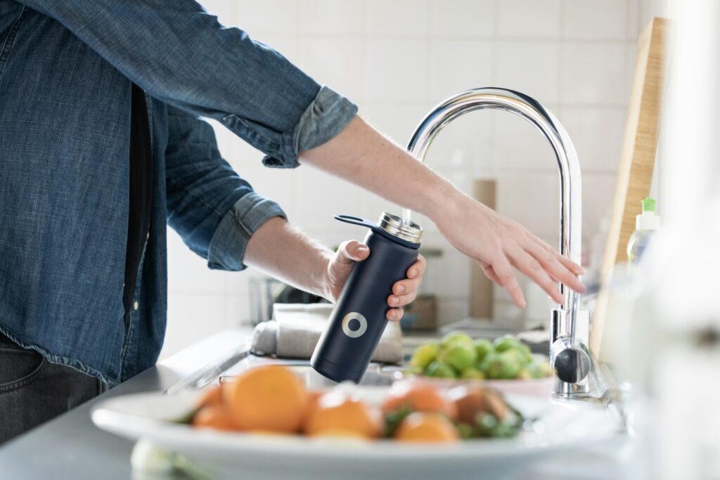 A person filling up their water bottle from a tap 