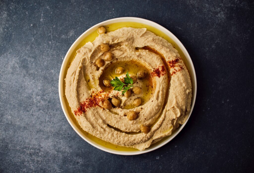 A bowl of hummus with chickpeas on top 