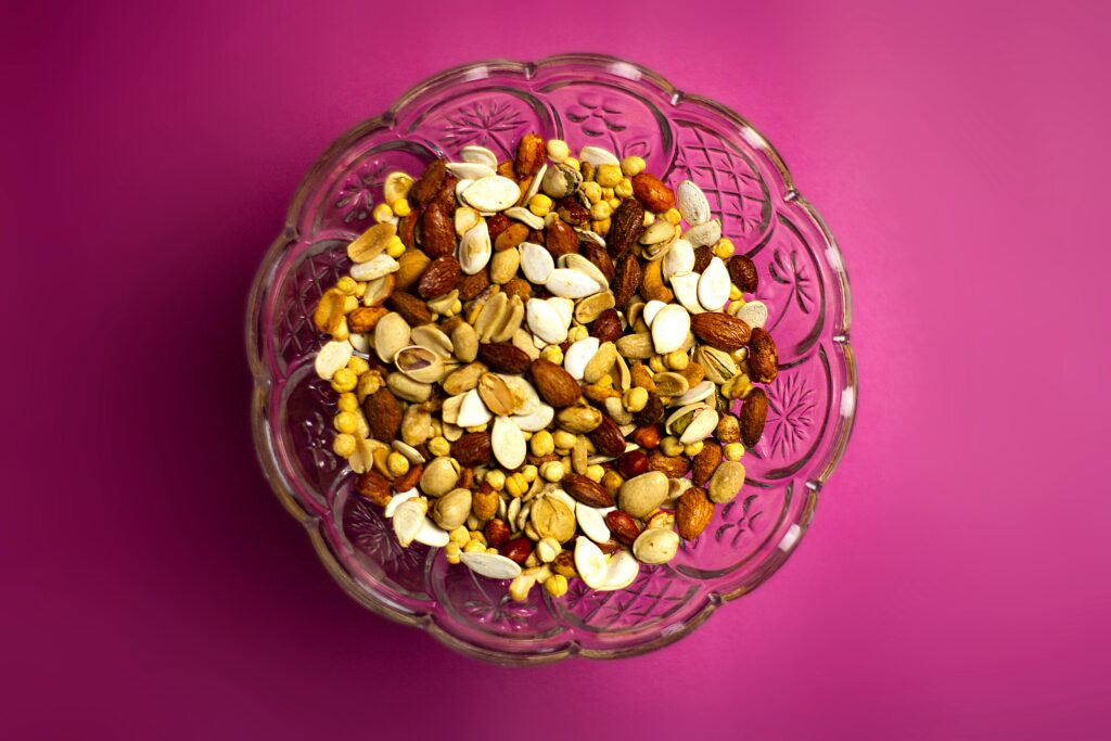 A bowl of mixed nuts with a pink background 