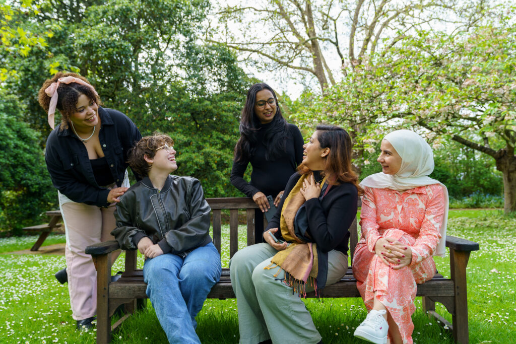 5 international students sitting on a bench talking to eachother 