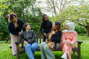 5 international students sitting on a bench talking to eachother