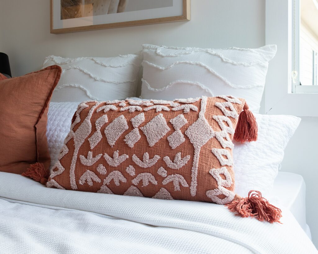 A peach decorative pillow on a bed 