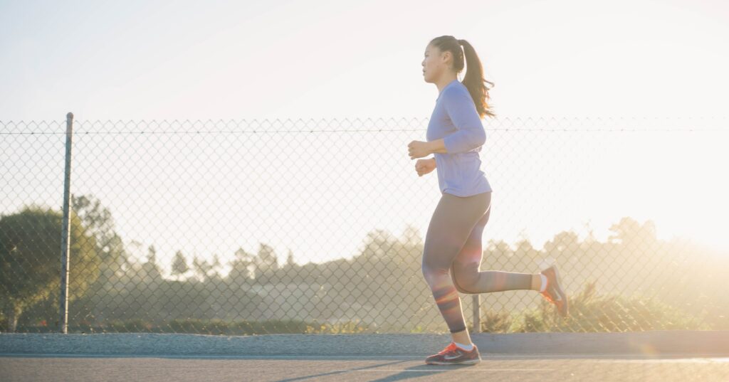 A women is running at sunrise with her gym set on. 