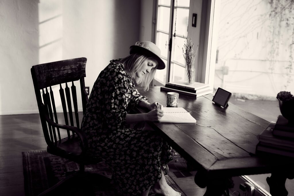 A black and white photo of a woman typing one her laptop 