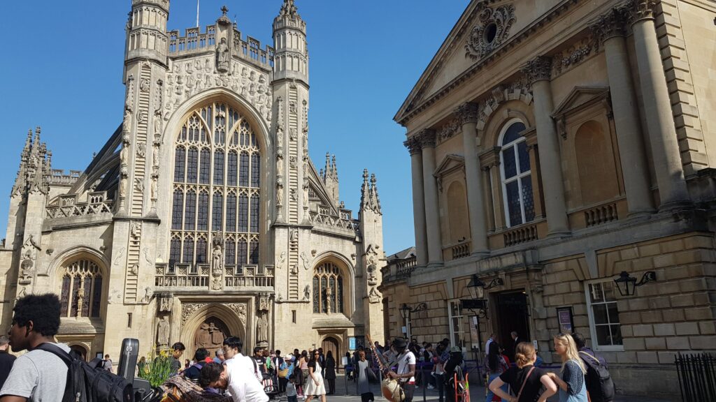 A picture of a historical building in bath whilst people are walking around