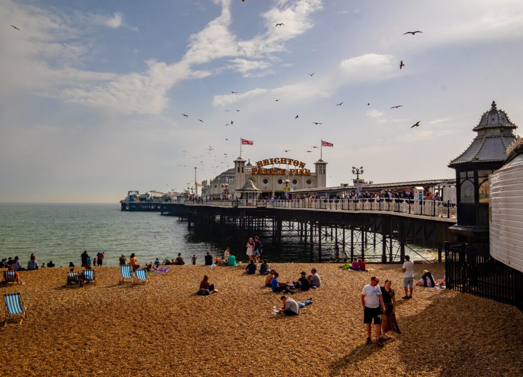 Brighton pier with people sitting on the beach and at the fun fair 