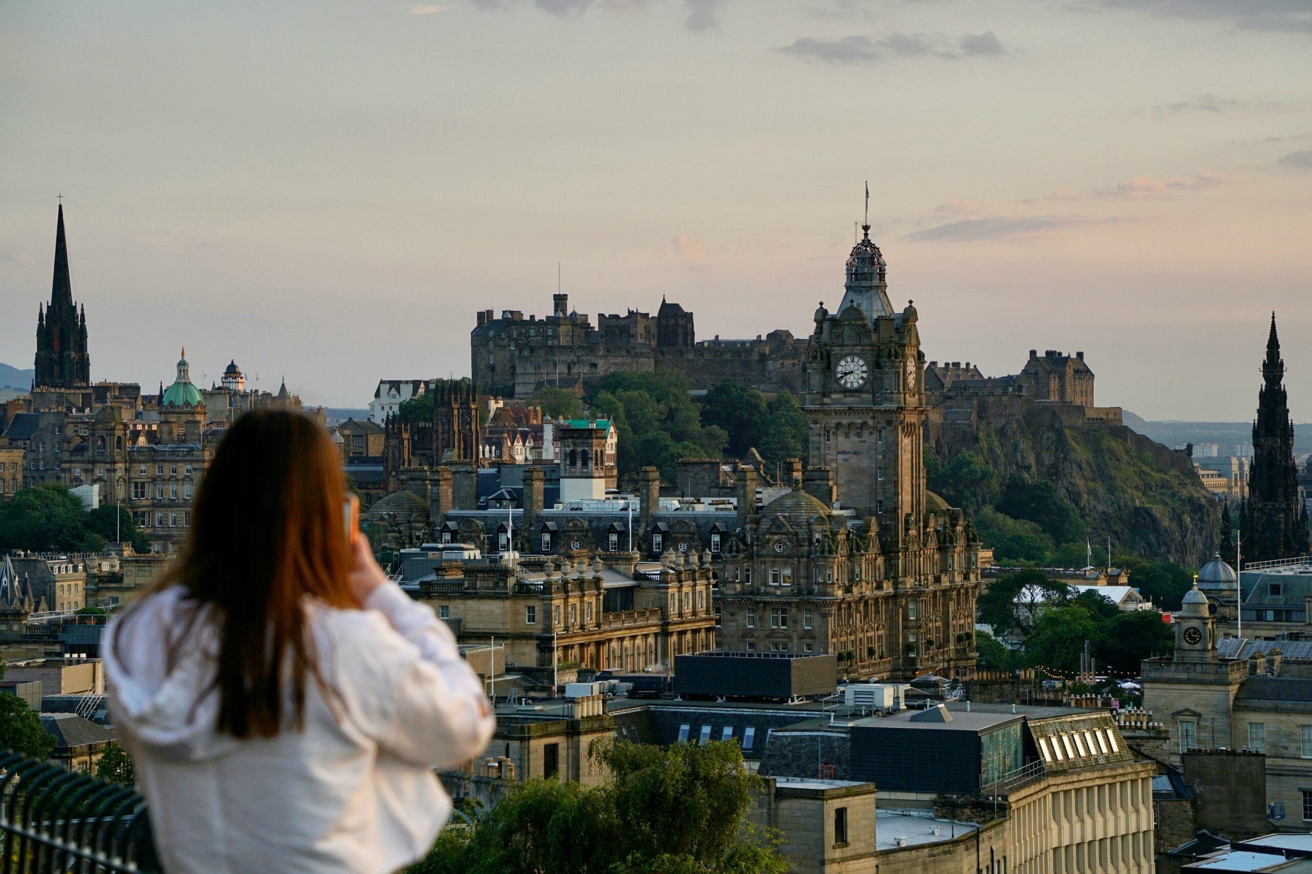 A woman taking a picture of Edinburgh buildings