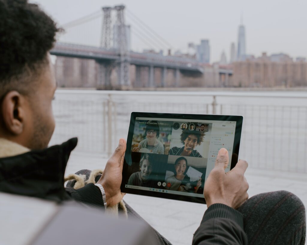 A man video calling people with a view of a bridge behind him 