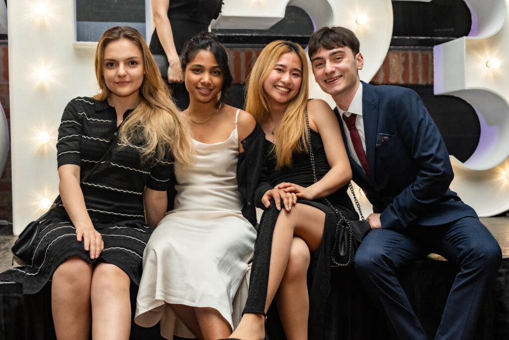 4 people sitting next to each other taking a picture 