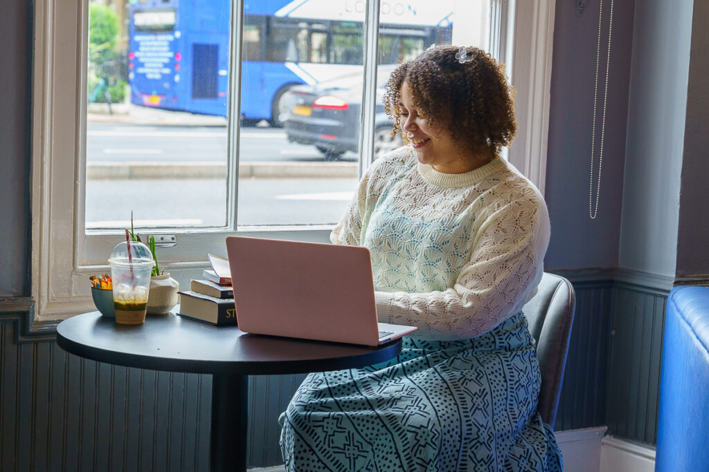 A Girl sitting down at a coffee shop with her laptop open 