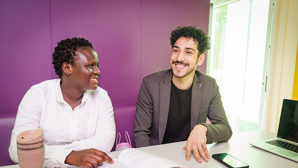 two international students smiling while sitting in a booth in ISH reception area