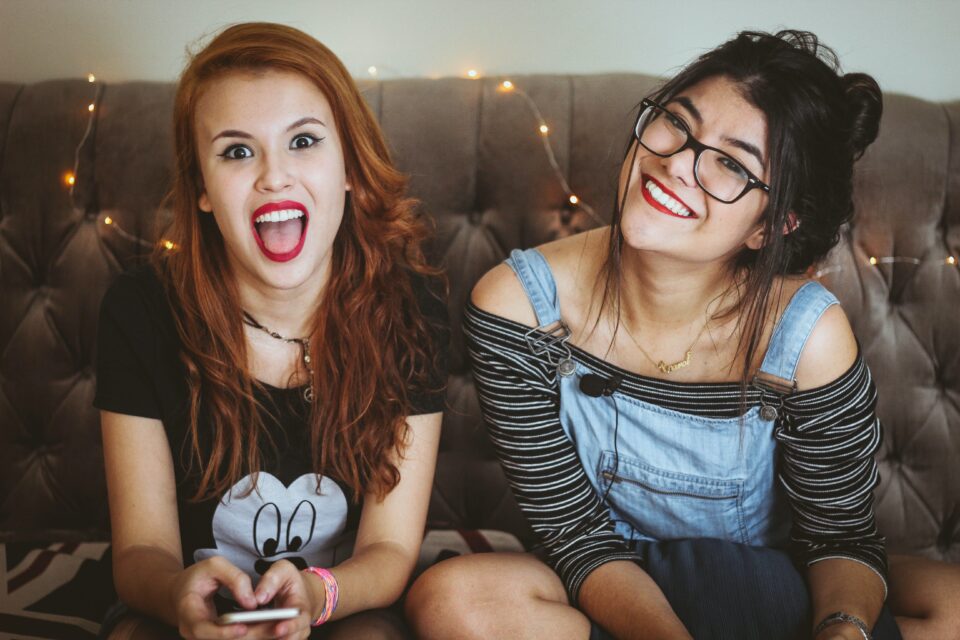 Two friends looking at the camera smiling in their room