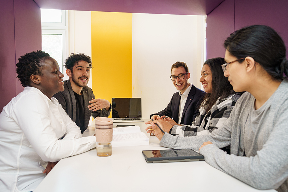 a group of residents discussing life skills in a booth at the international students house