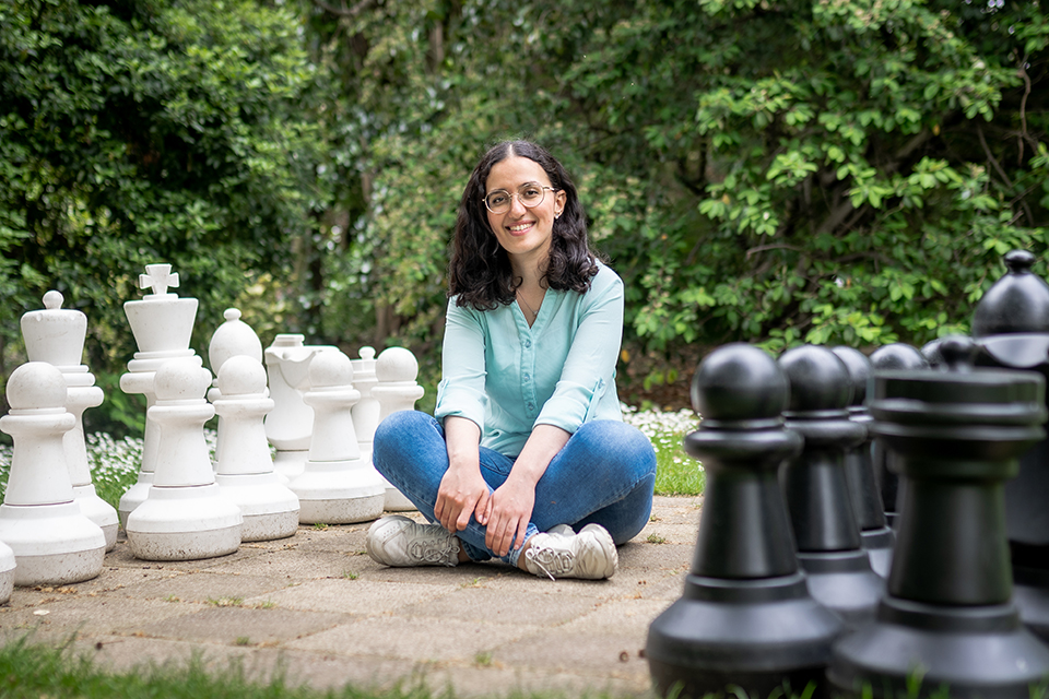 International Students House resident sitting among a life-size chess board in the park