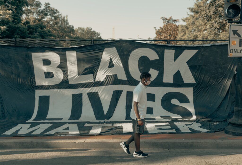 A man walking past a Black Lives Matter banner
