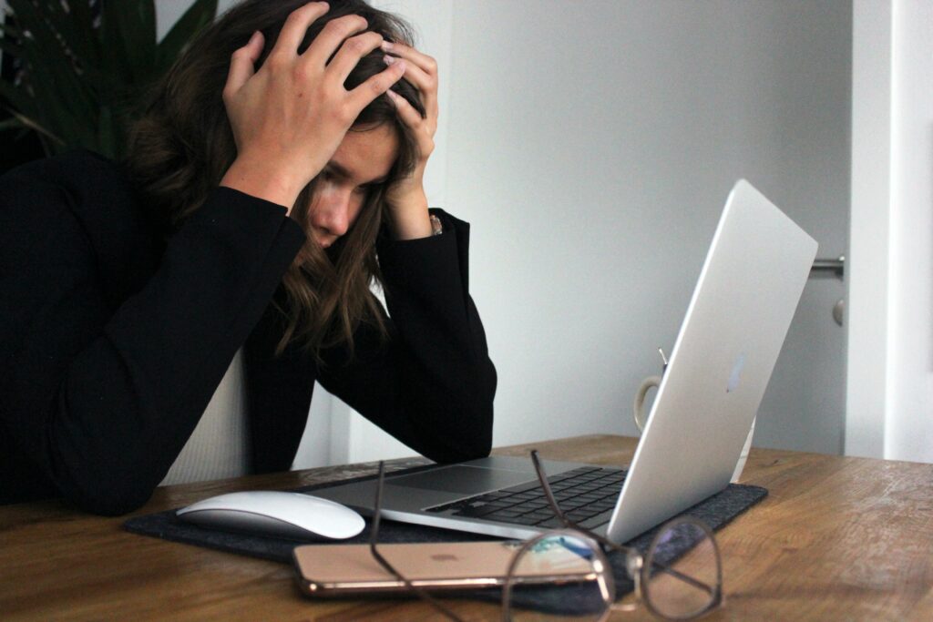 A woman putting her hands on her head looking at her laptop