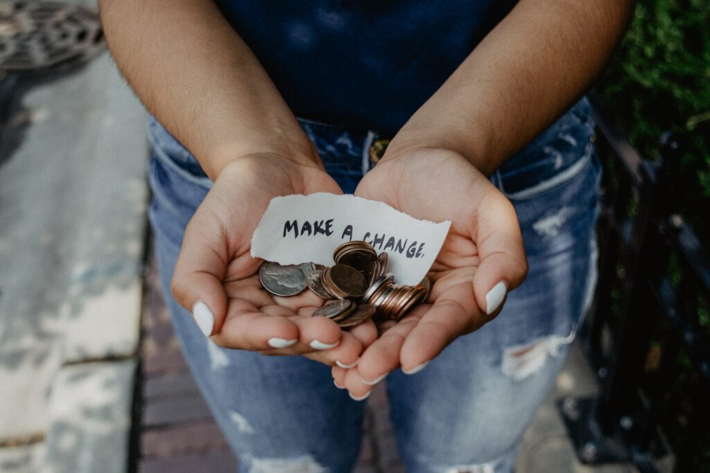 A person holding a small amount of money in their hands with the word make a change inside her palms 
