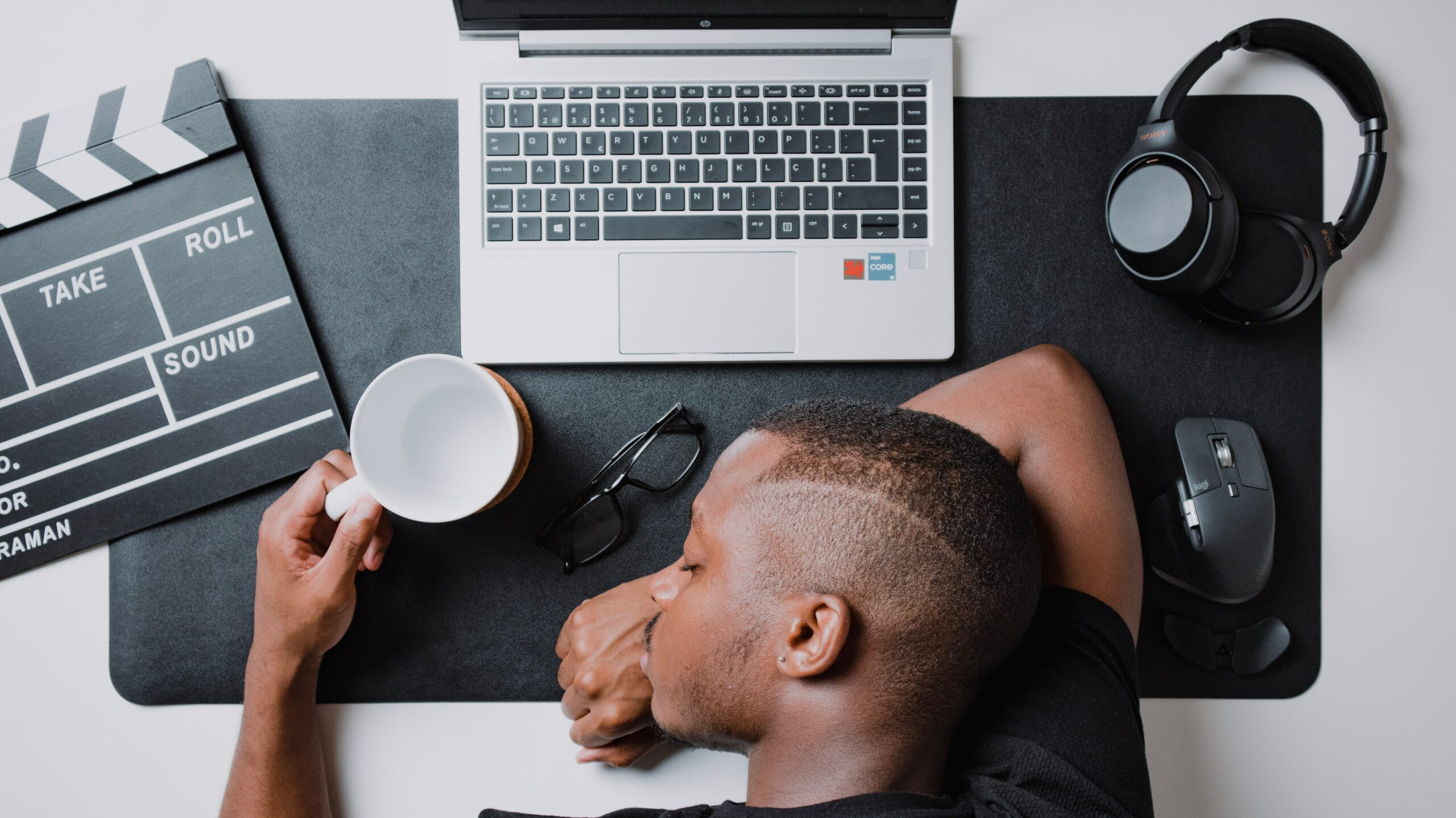 A man sleeping at his desk with his laptop open