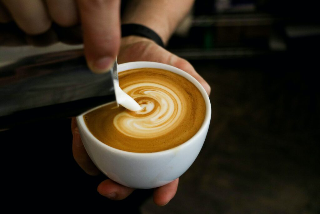 A person adding milk into a latte
