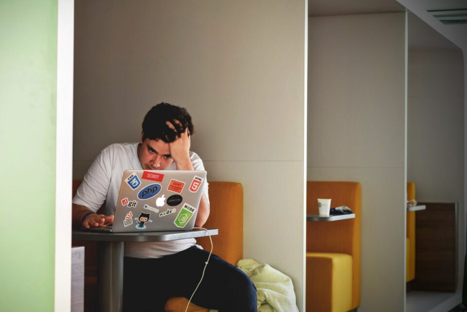 A man looking at his laptop with his hands on his head