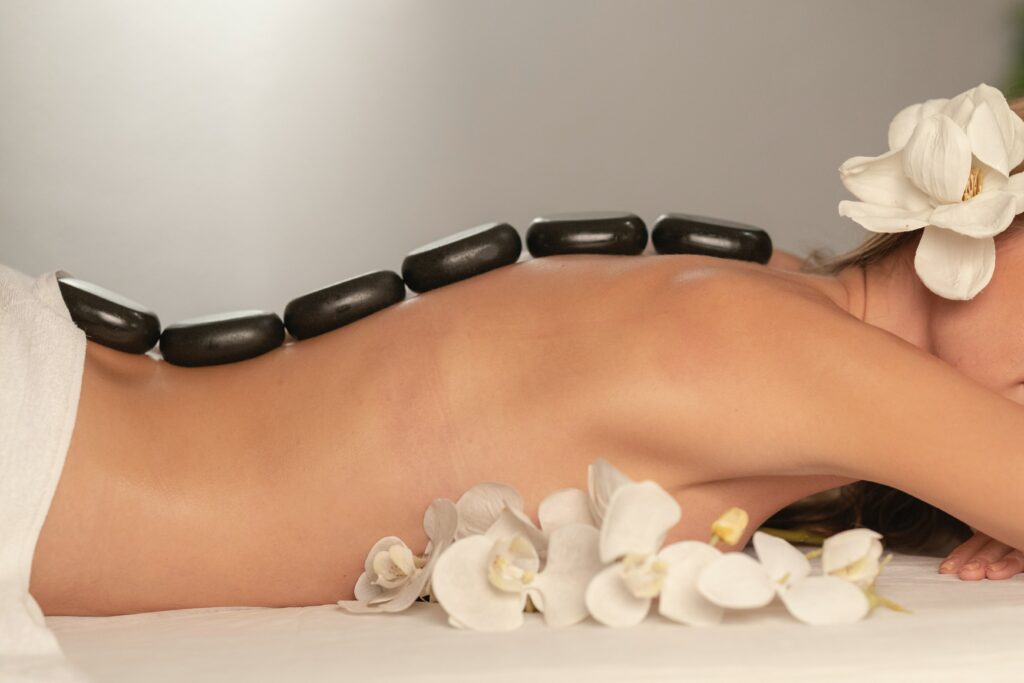 A woman using hot stones on her back whilst lying down 