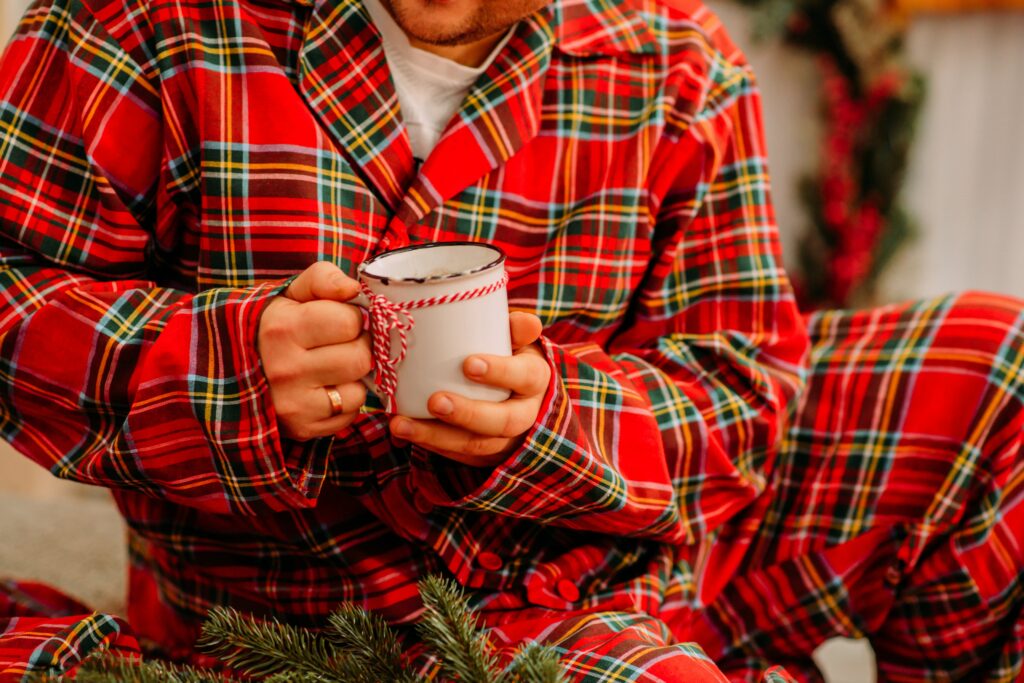 A person holding a hot drink whilst wearing red pyjamas 