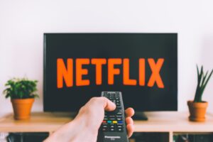 Someone pointing their remote to their TV screen with the Netflix logo on it
