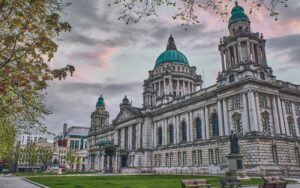 A picture of a city hall in Belfast with trees on the side of it