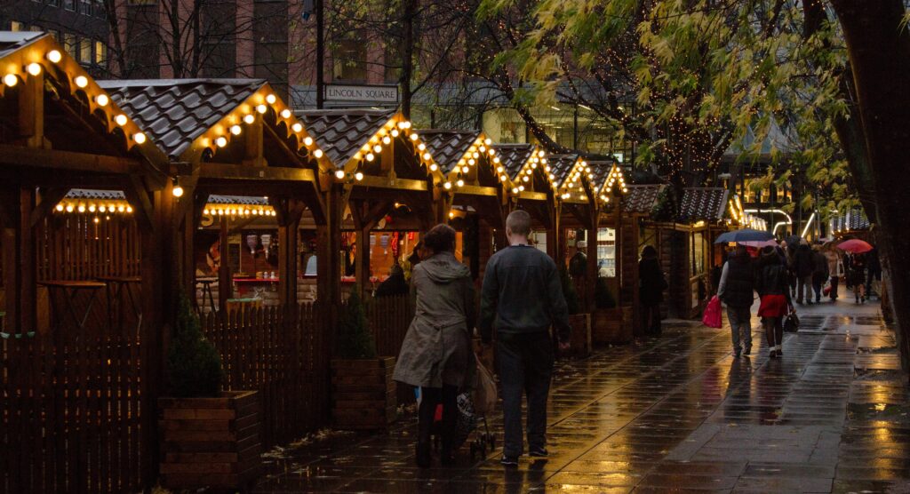 A couple walking past some Christmas stalls at the Christmas market 