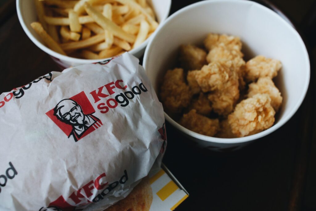 A bucket of chicken from KFC with chips on the side 