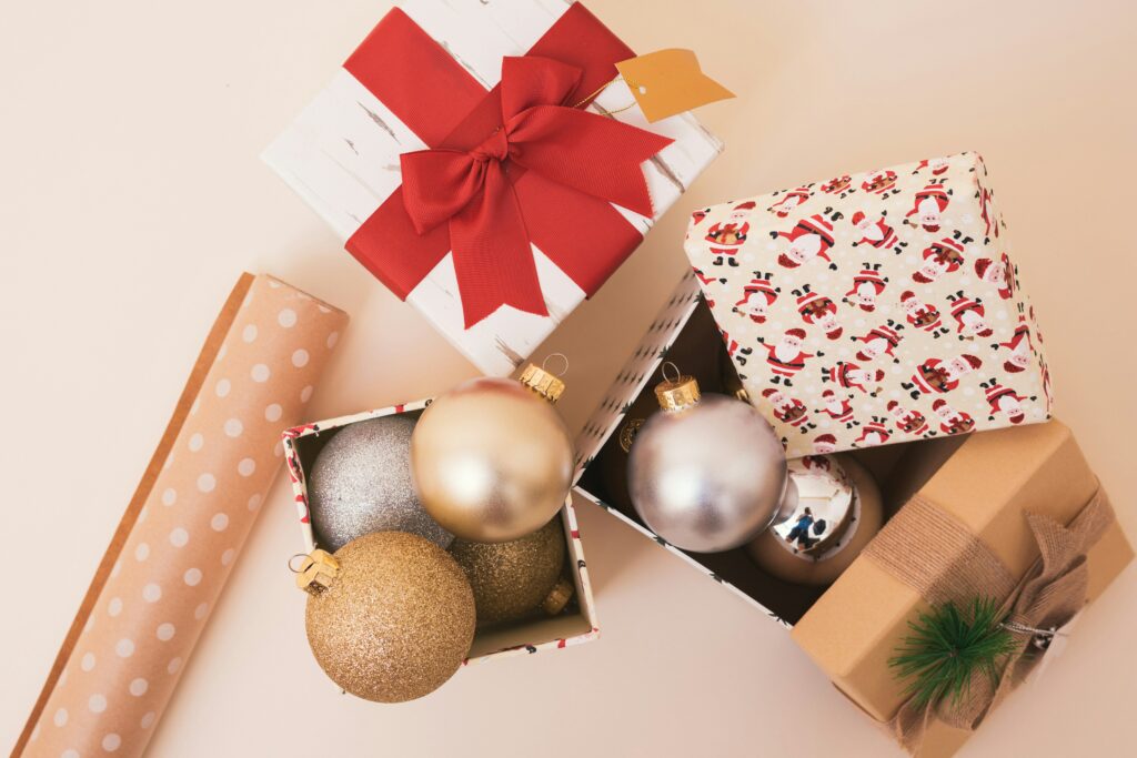 a box of Christmas ornaments with some wrapping paper next to it 