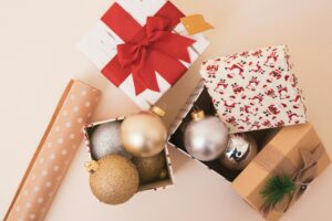 a box of Christmas ornaments with some wrapping paper next to it