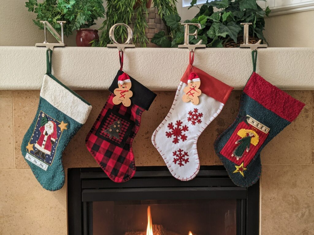 4 Christmas stocking handing form a fireplace with the word Noel on top of it 