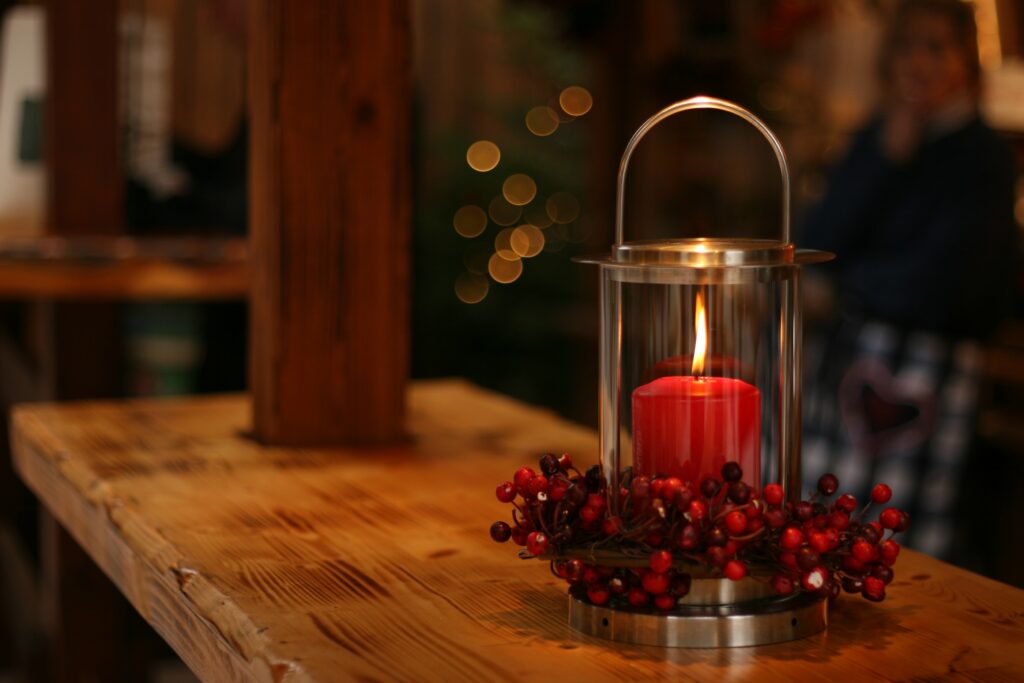 A red candle inside a glass container with cranberries on the bottom of it 