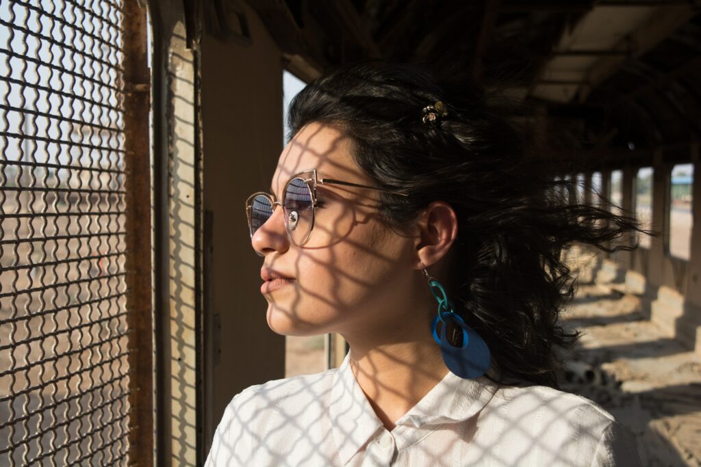 A woman looking through a fence at the sunlight