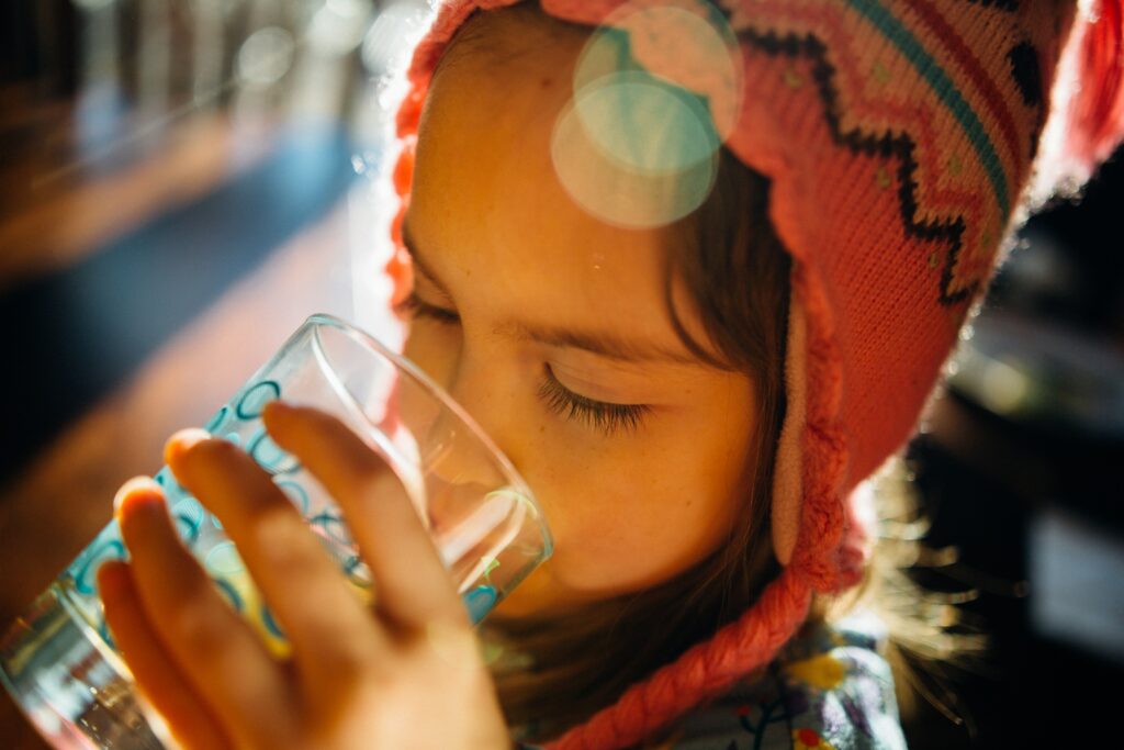 A little girl drinking a glass of water 