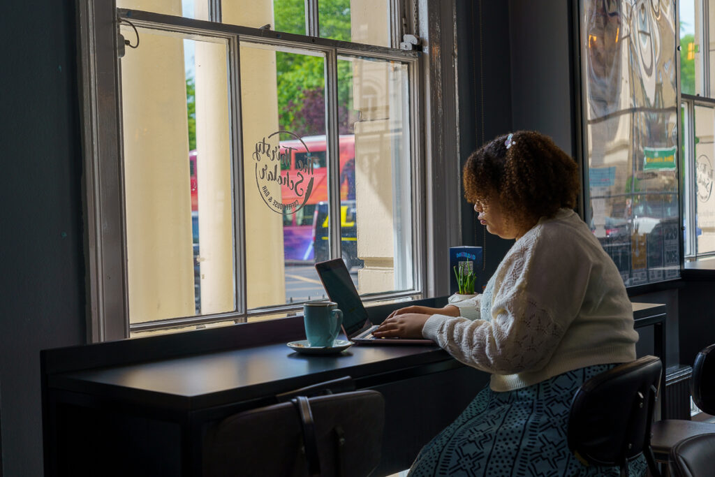 A girl sitting in a coffee shop with her laptop.