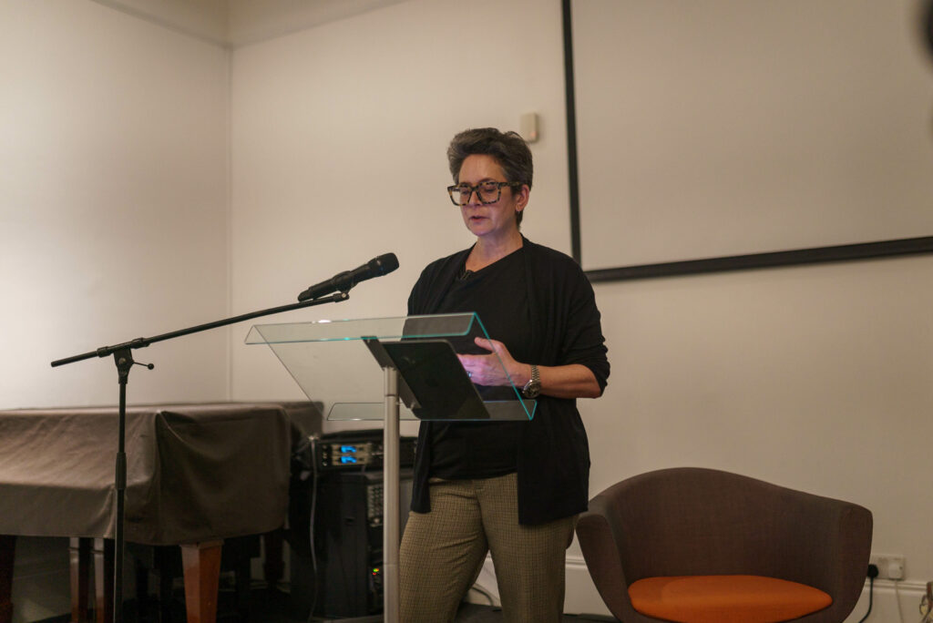 A woman standing talking into a mic