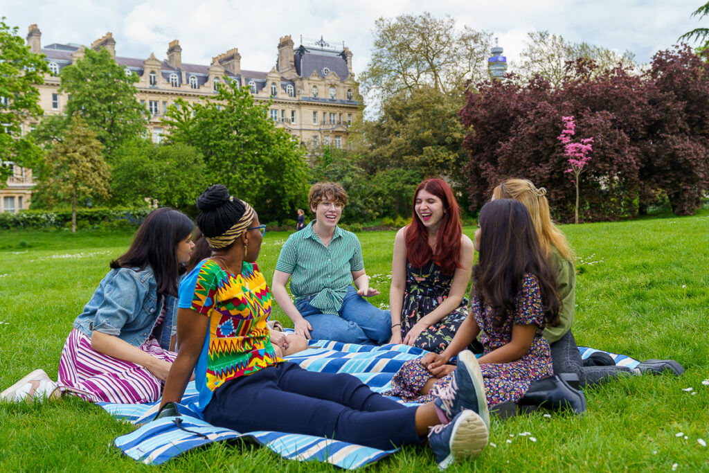 A group of people sitting on the grass talking 