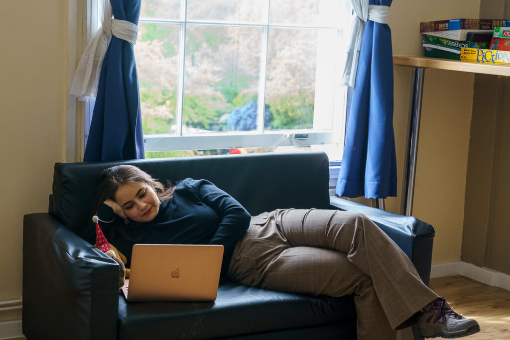 A girl laying down on the couch with her laptop