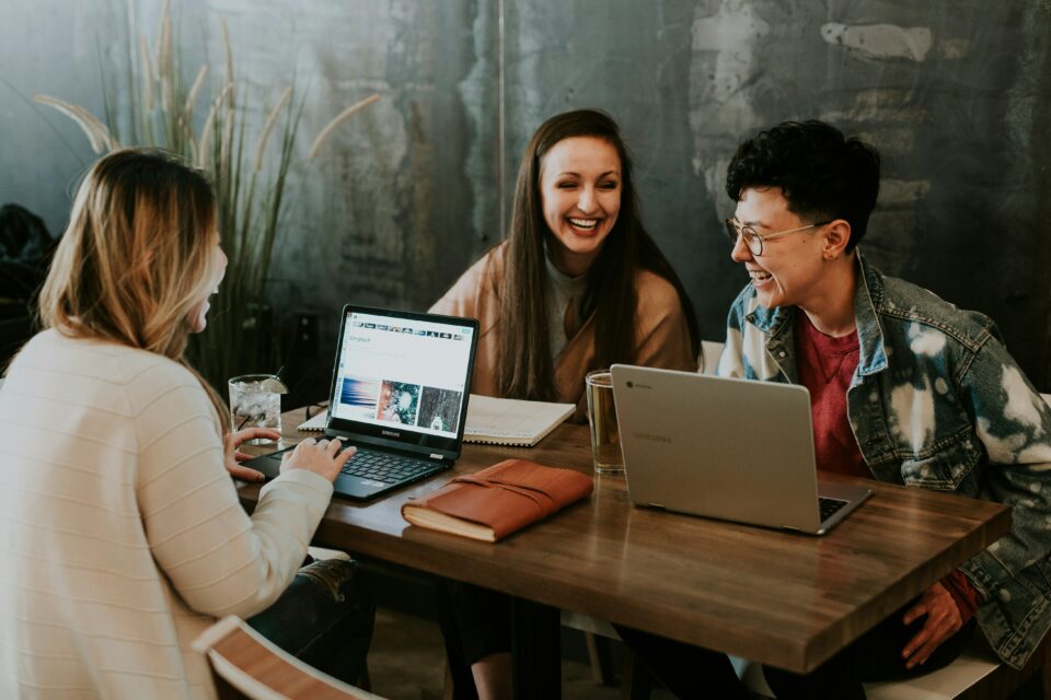 Three women laughing with their laptops open on their desk