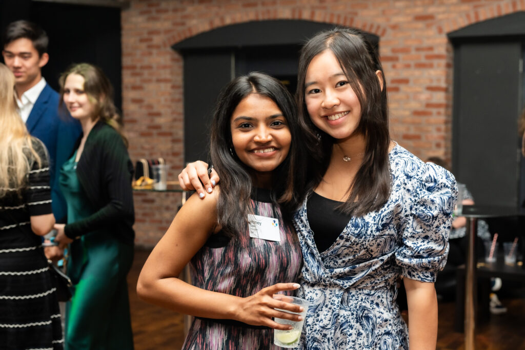 Two women giving each other a hug whilst looking at the camera 