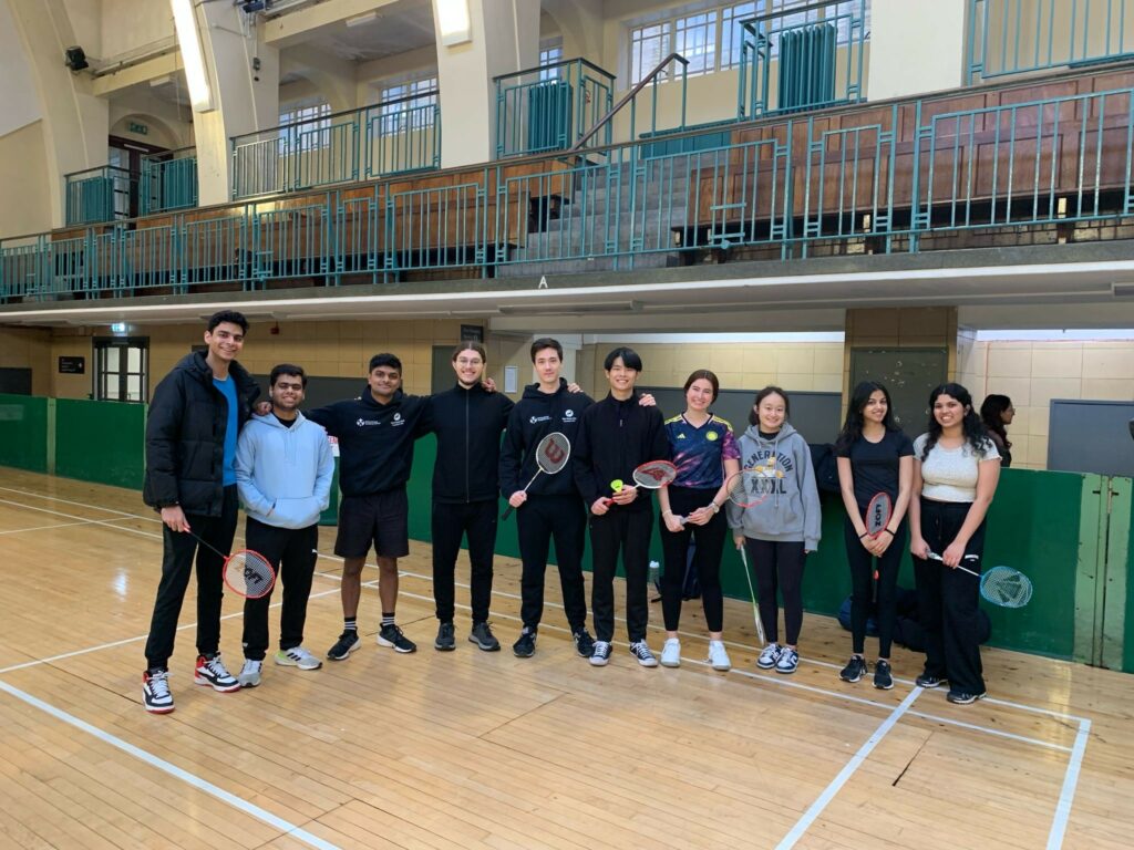 A group of people holding rackets on a badminton court 