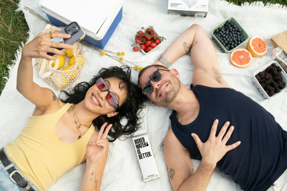 A woman and Man laying down on a blanket in the park